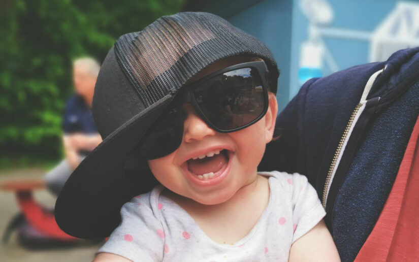 Lachendes Kind mit Sonnenbrille und Baseball-Cap