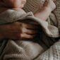 Mutter sitzt mit Baby am Fenster, ruhige häusliche Szene als Sinnbild für Familien, die von der geplanten Elterngeld-Kürzung 2027 betroffen sind